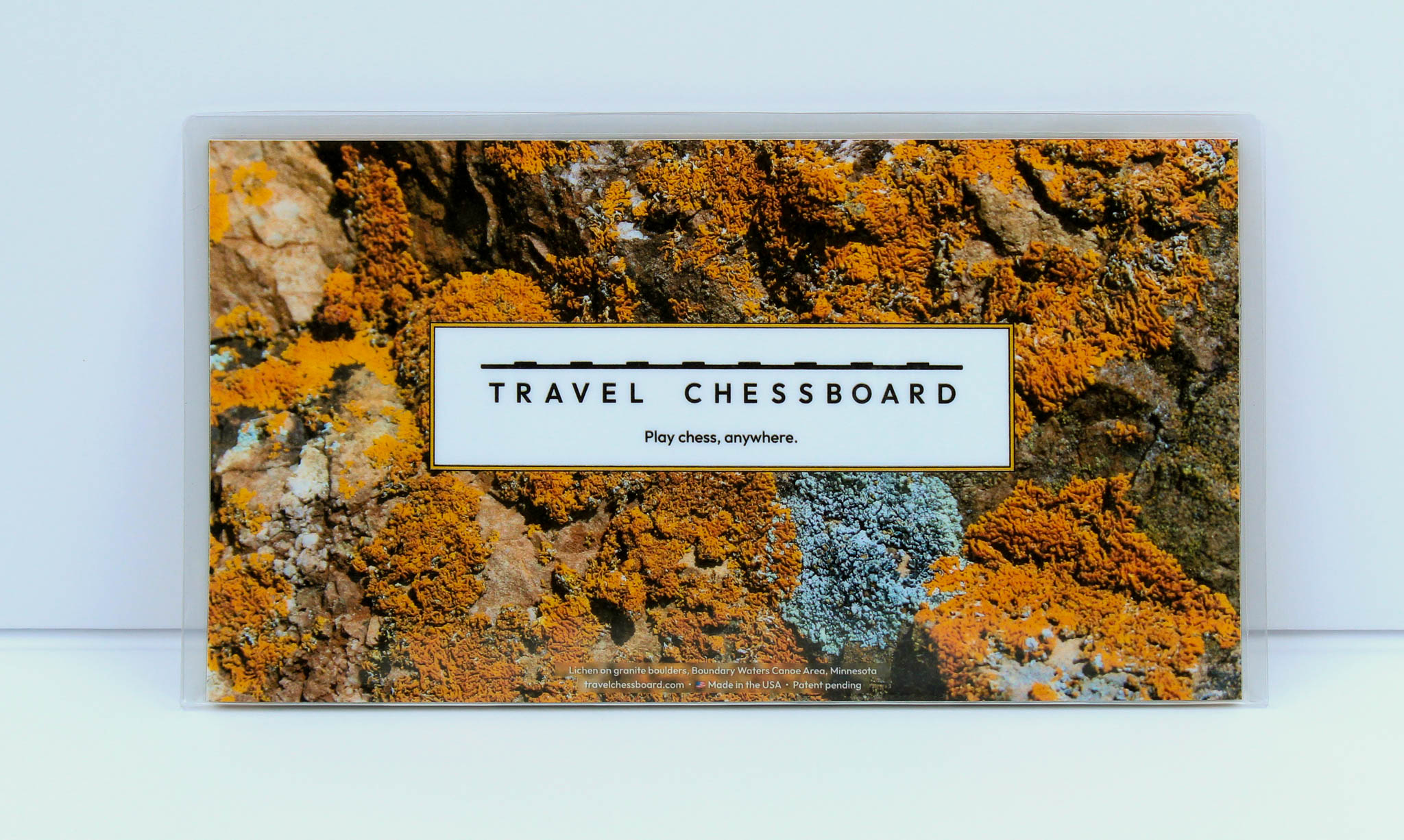A closed Travel Chessboard with Orange Lichen design on a white background.