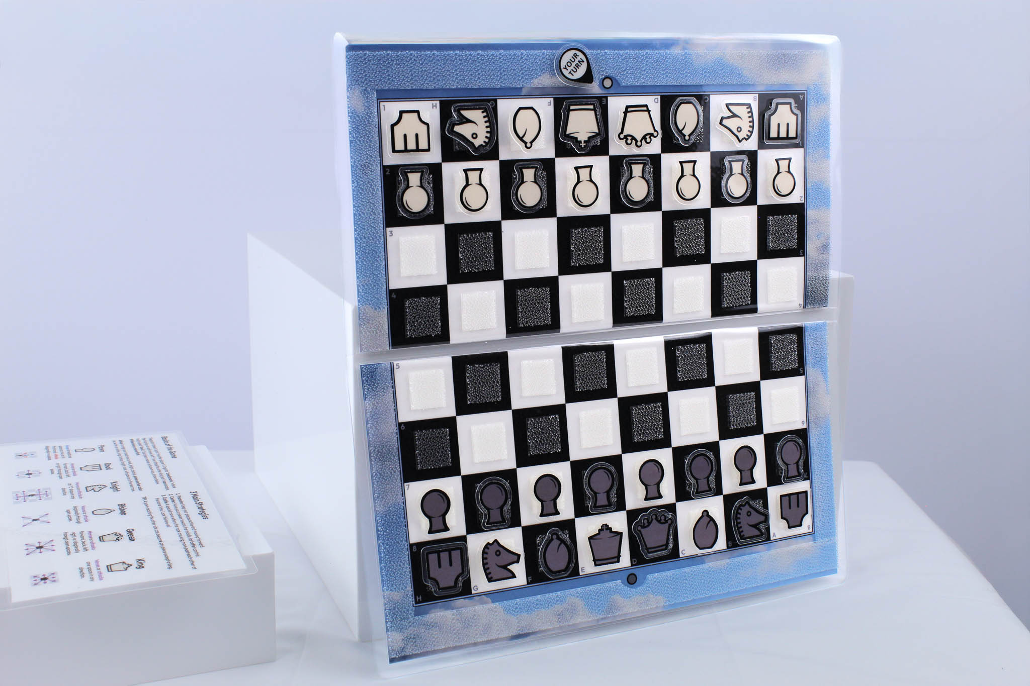 Blue Sky Travel Chessboard open and upright on a white background next to a "how to play" insert laying down flat.